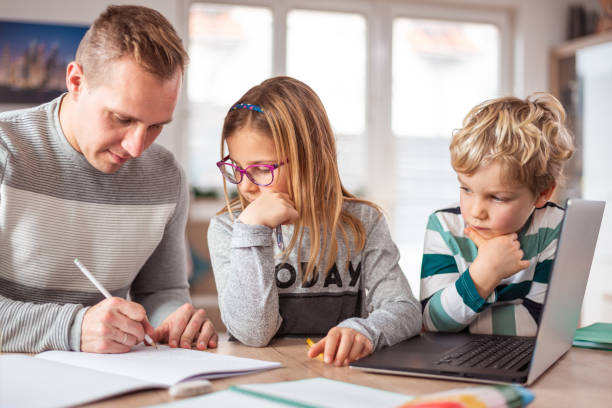 istock Father with his two children doing homework at home 1300158889