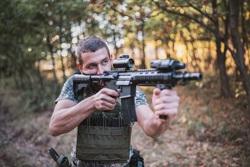 Portrait of a soldier in a forest holding his weapon.