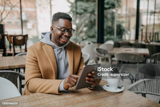 Young Freelancer Using Tablet Stock Photo - Download Image Now - Coffee Shop, Working, Men