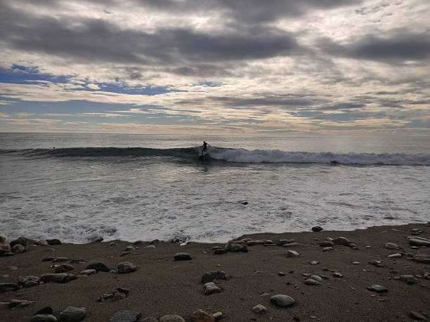 istock Surfer in the sea at dusk with cloudy dramatic sky 1300168397