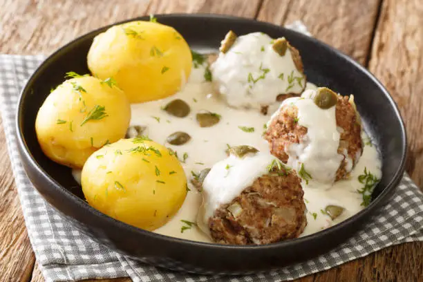 Tasty German Konigsberger Klopse meatballs in caper sauce served with boiled potatoes close-up in a plate on the table. horizontal