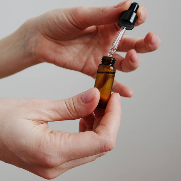 istock Essential oil falling from a glass dropper on the gray background 1300172121