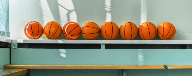 les boules oranges de panier sont en ligne sur le stand en bois dans la salle de gymnase. - cultural center photos et images de collection