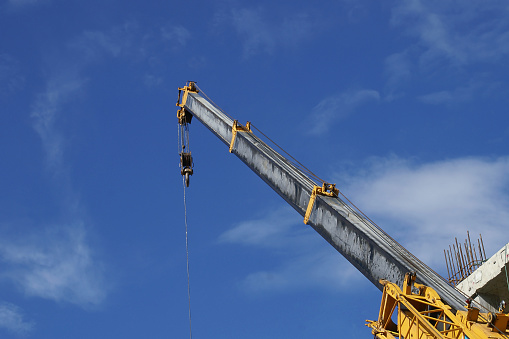 Yellow Telescopic Arm of a Mobile Crane at a Construction Site against Blue Sky