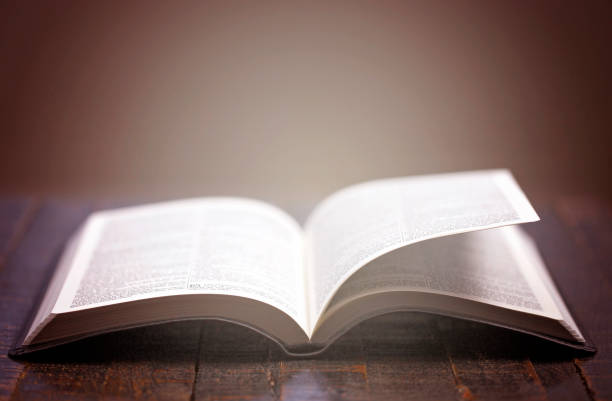 istock Bible Open on a Rustic Wooden Table with Pages Blowing Open 1300177939
