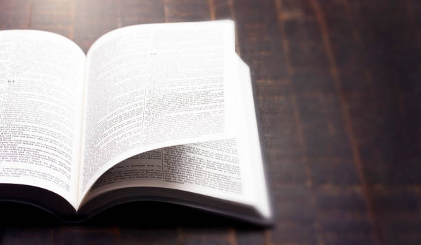 istock Bible Open on a Rustic Wooden Table with Pages Blowing Open 1300177941