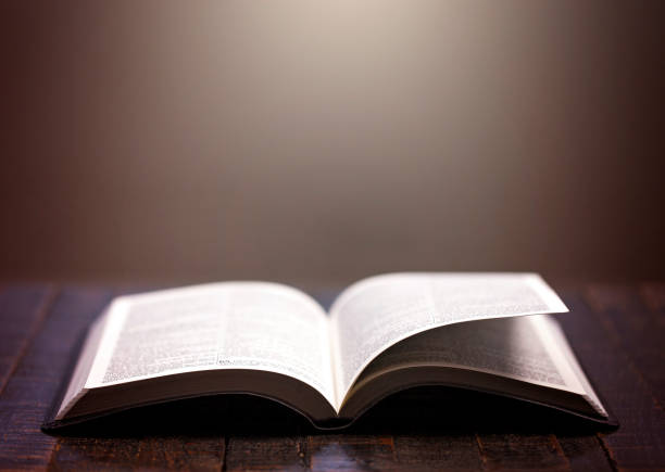 istock Bible Open on a Rustic Wooden Table with Pages Blowing Open 1300177980