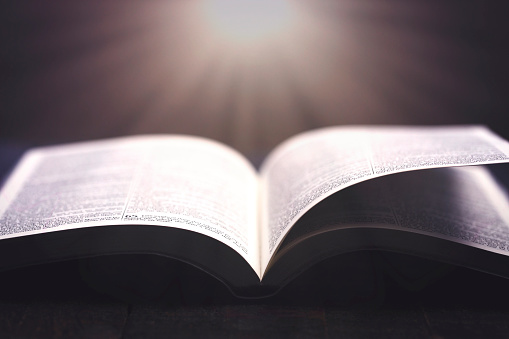 Bible Open on a Rustic Wooden Table with Pages Blowing Open