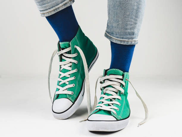 istock Green sneakers and funny socks on a white background 1300180836