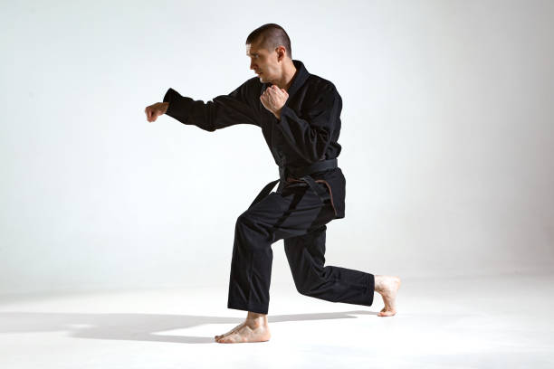 istock Athletic guy trainer in black kimono fighter showing karate technique on studio background with copy space 1300184724