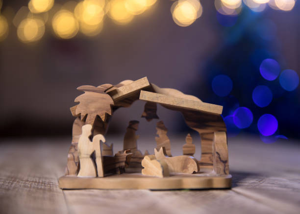 Christmas nativity scene with wooden figures. Mary, Joseph, shepherd and magi (three wise men) are standing near the manger of Jesus Christ in the cave. Candle as a hearth. Christmas decoration theme.