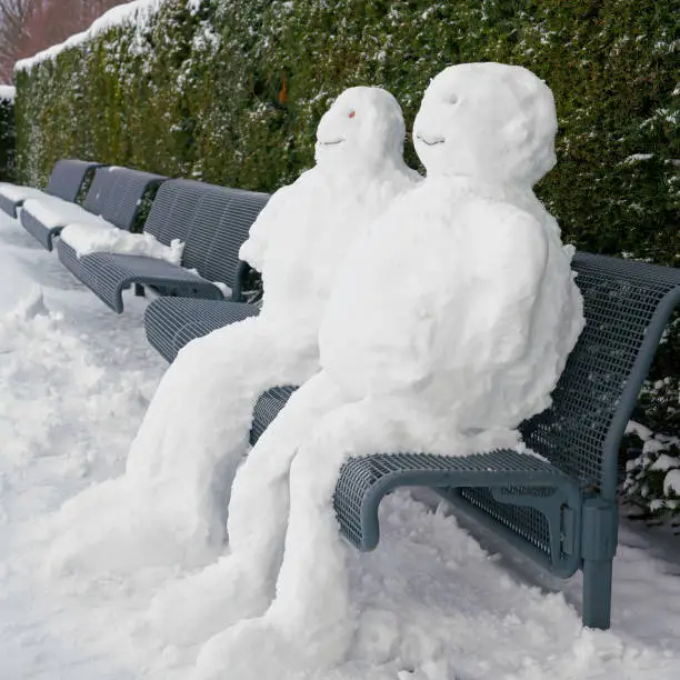 Snowman and snowwoman on a park bench in Magdeburg in winter