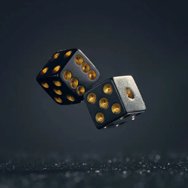 Photo of Two black dice are falling on a dark gray background.