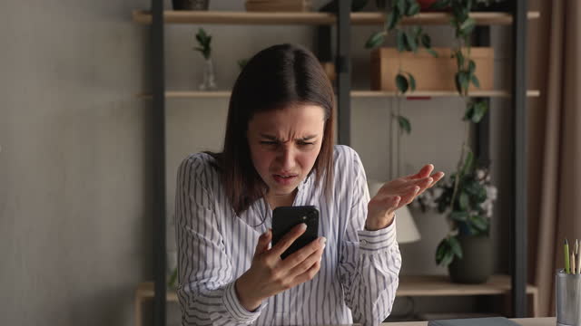 Stressed nervous young woman looking at cellphone screen.