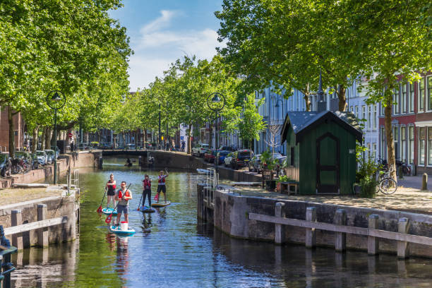Young people paddling through the canals of Gouda Young people paddling through the canals of Gouda, Netherlands gouda south holland stock pictures, royalty-free photos & images