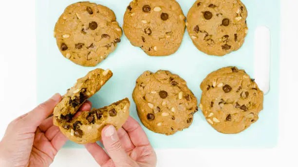 Photo of Chocolate Chip Cookies with pine nuts close up on a serving board. Homemade old-fashioned Chocolate Chip Cookies. American cuisine, dessert