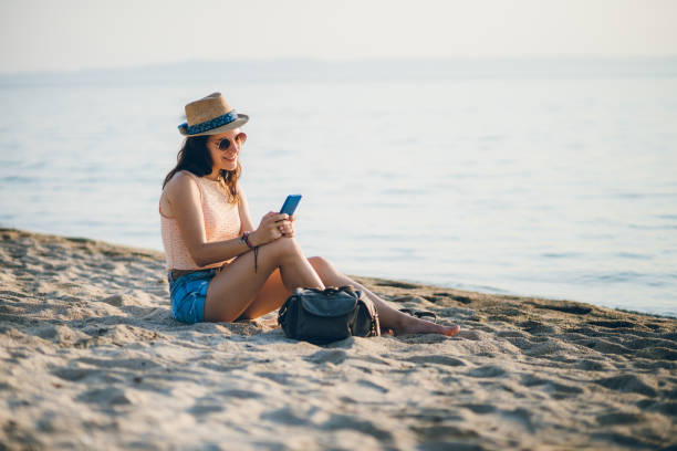 istock Woman at the beach texting on smartphone 1300193239