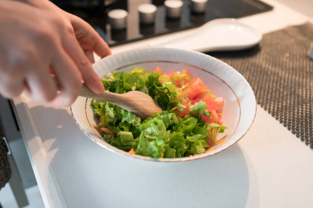 Human hands are mixing salad of fresh vegetables