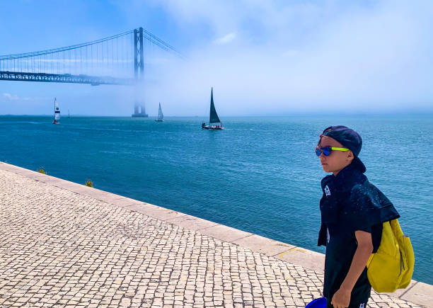 Taken on Mobile Device a boy walks along the Tagus river embankment in the fog