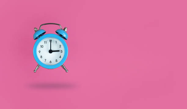 istock Levitating blue alarm clock on pink background with copy space. 1300195385