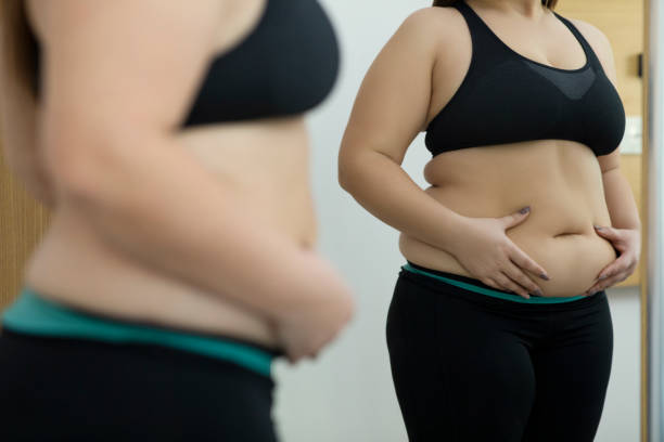 mujer con abdomen gordo - dieting mirror healthy lifestyle women fotografías e imágenes de stock