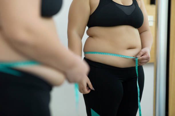 female measures her waist - overweight women body abdomen imagens e fotografias de stock