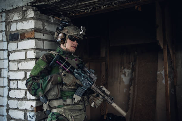 istock Military man with assault rifle standing inside building, he is ready for combat 1300196503