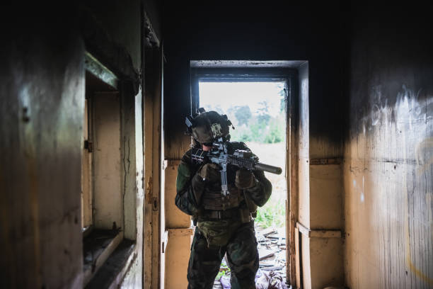 istock Soldier in full US MARSOC equipment entering abandoned building, aiming different angles with MK18 assault rifle 1300196542