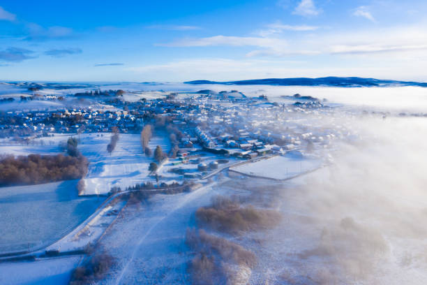 la vista aerea da un drone di una piccola città scozzese in una nebbiosa mattina d'inverno dopo una caduta di neve - galloway foto e immagini stock