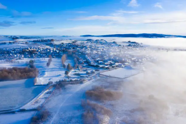 Photo of The aerial view from a drone of a small Scottish town on a misty winter morning after a fall of snow