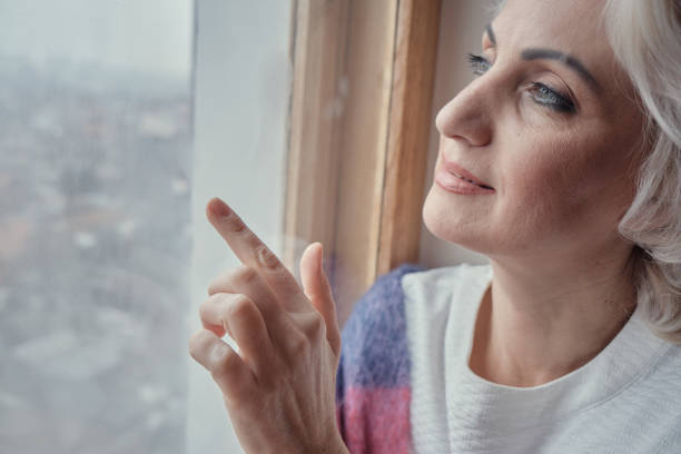 istock Pensive mature woman drinking tea and looking out window, lockdown and isolation concept, selective focus 1300197794