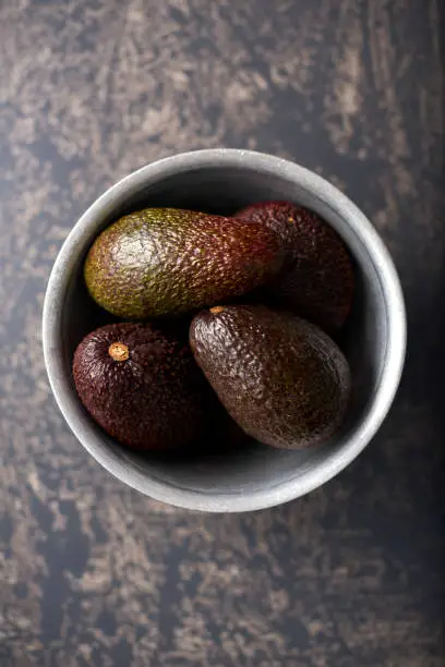 Overhead shot of a bowl of Avocados against a mottled background