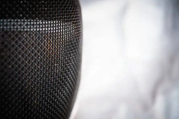 Extreme close up of fencing mask, sport equipment protection safety selective focus on foreground and copy space