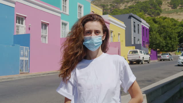 Woman masked during quarantine in the streets of colorful buildings neighbourhood Bo-Kaap Cape Town South Africa.