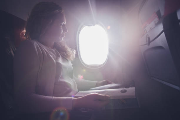 istock Serious female passenger reading newspaper in airplane. 1300210446