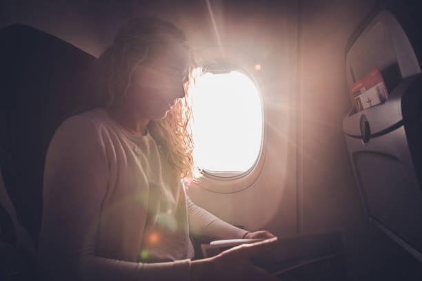 istock Female passanger reading newspaper in airplane. 1300210518