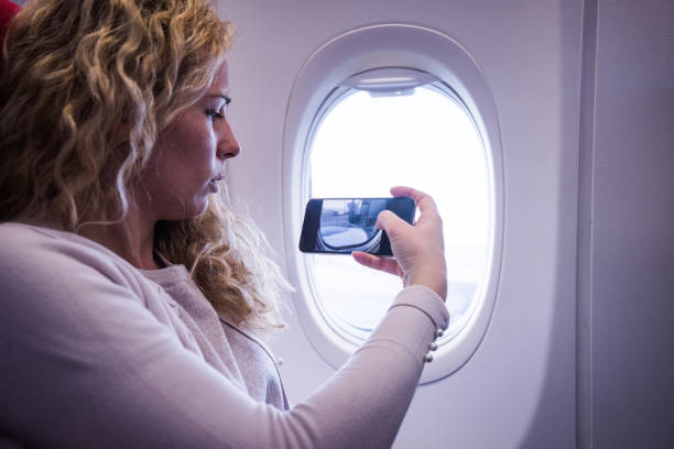 istock Young woman taking a picture from an airplane. 1300210559