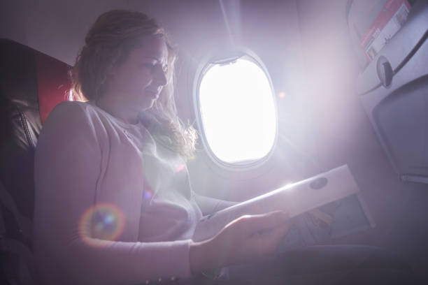 istock Female passenger reading newspaper in airplane. 1300210585