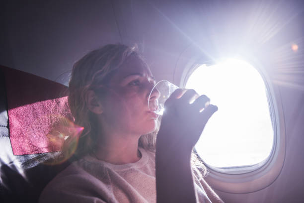 istock Young female drinking water in airplane. 1300210625
