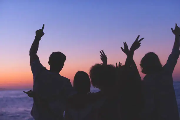 Photo of Group of people partying on the beach at sunset or sunrise.