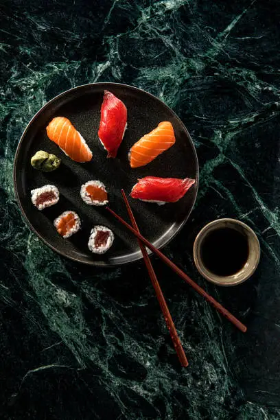 Photo of Salmon and Tuna sushi with soy sauce over green marble background