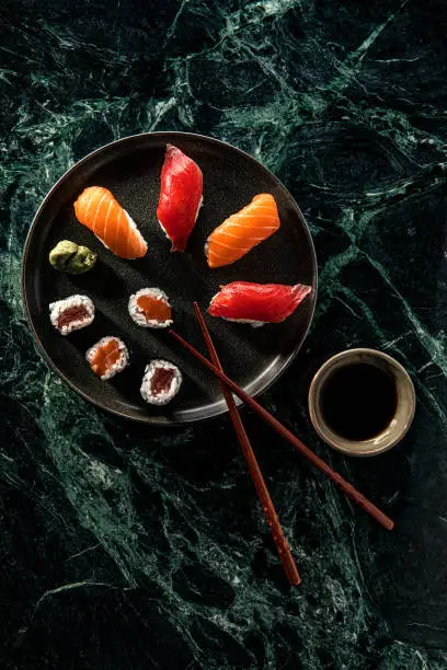 Salmon and Tuna sushi with soy sauce over green marble background
