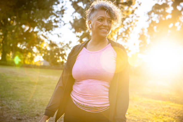 Black woman walking in the sunset Senior black woman working out walking with the sun at her back. womens issues photos stock pictures, royalty-free photos & images
