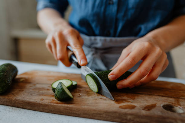 Hands of a Woman Chopping Cucumbers on a Cutting Board Anonymous woman chopping fresh vegetables for a salad, a close up. chopping food stock pictures, royalty-free photos & images