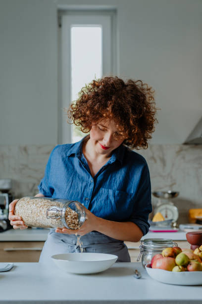 istock Making a Healthy and Nutritious Breakfast: Smiling Woman Pouring Rolled Oats into a Bowl 1300217006