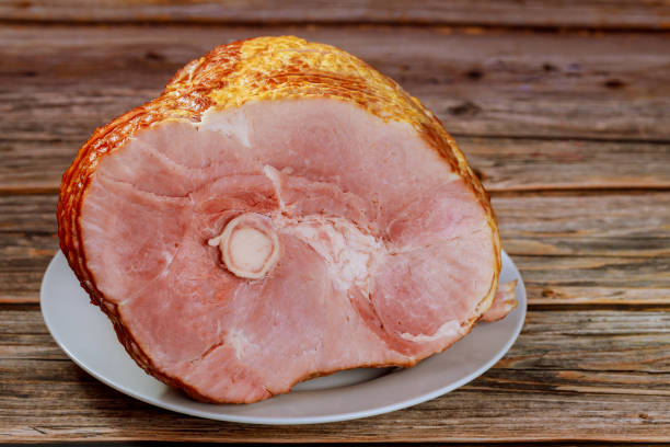 istock Hickory smoked spiral sliced ham on wooden background. 1300224755