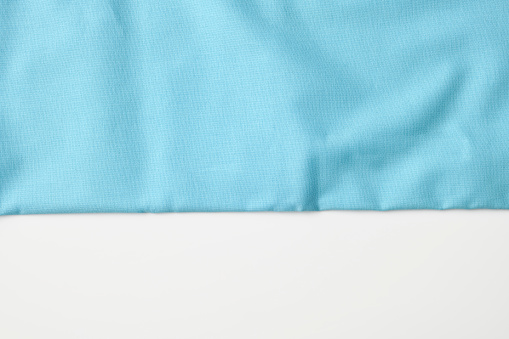 Overhead shot of light blue cloth boarder texture on white background.