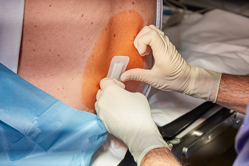 Doctor applying a patch on the Patient's back after the Epidural procedure