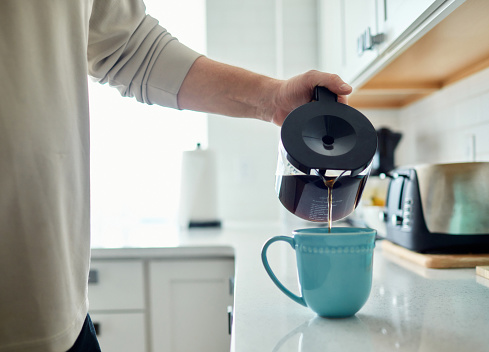 Unrecognizable male filling coffee mug with coffee