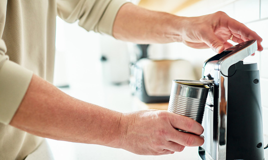 Unrecognizable male opening a can of food with an electric can opener